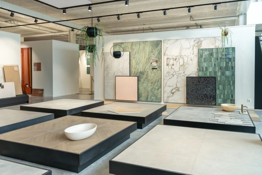 Verschuifbare rekken met grote, natuursteen look, zandkleurige tegels in de showroom van TÉGL