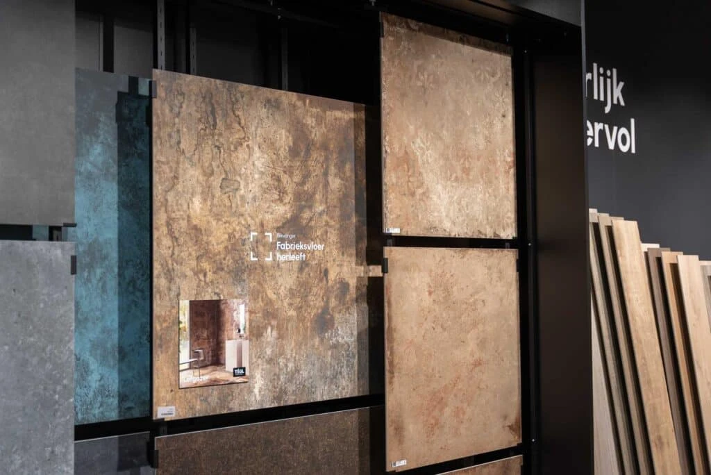 Verschuifbare rekken met grote, natuursteen look, zandkleurige tegels in de showroom van TÉGL