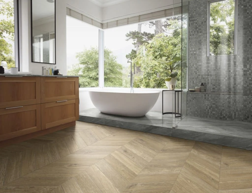 Luxe badkamer met grote ramen, houten wastafels, een vrijstaand bad en visgraat houtlook vloertegels voor een warme sfeer.