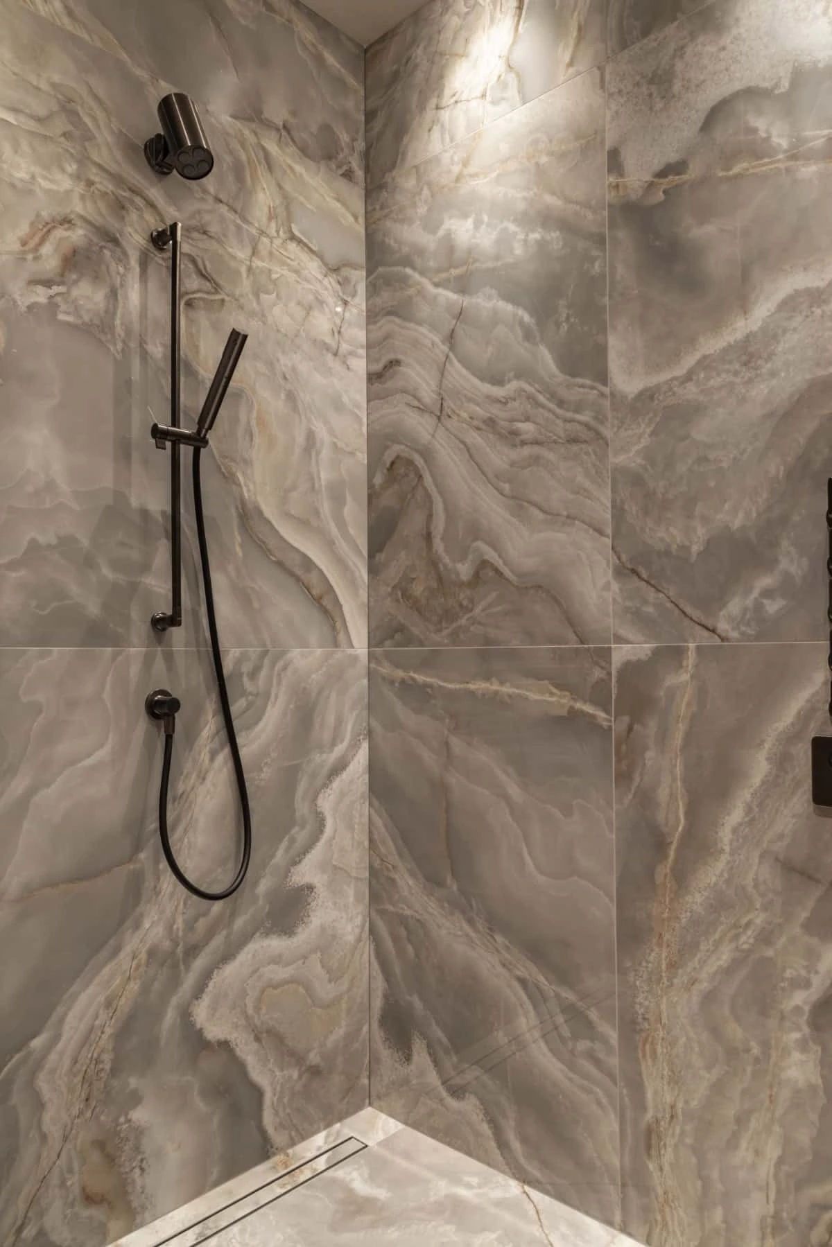 Moderne douche met luxe marmeren tegels en stijlvolle zwarte armaturen, die een elegante uitstraling aan de badkamer geven. Perfect voor een chique en tijdloze badkamerruimte.