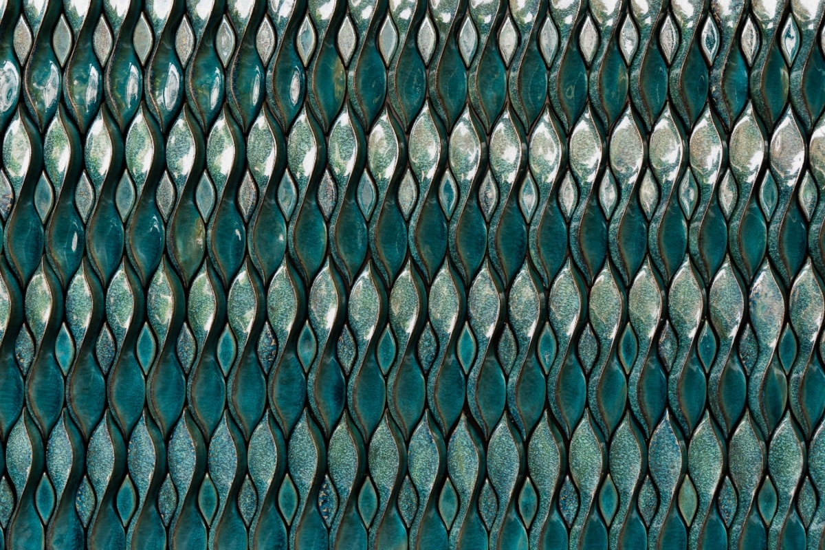 Een afbeelding van een reeks smalle, langwerpige tegels in een rijke, diepe blauwgroene kleur, waarbij de tegels glanzend zijn en een visuele textuur creëren die op vallende regendruppels lijkt.