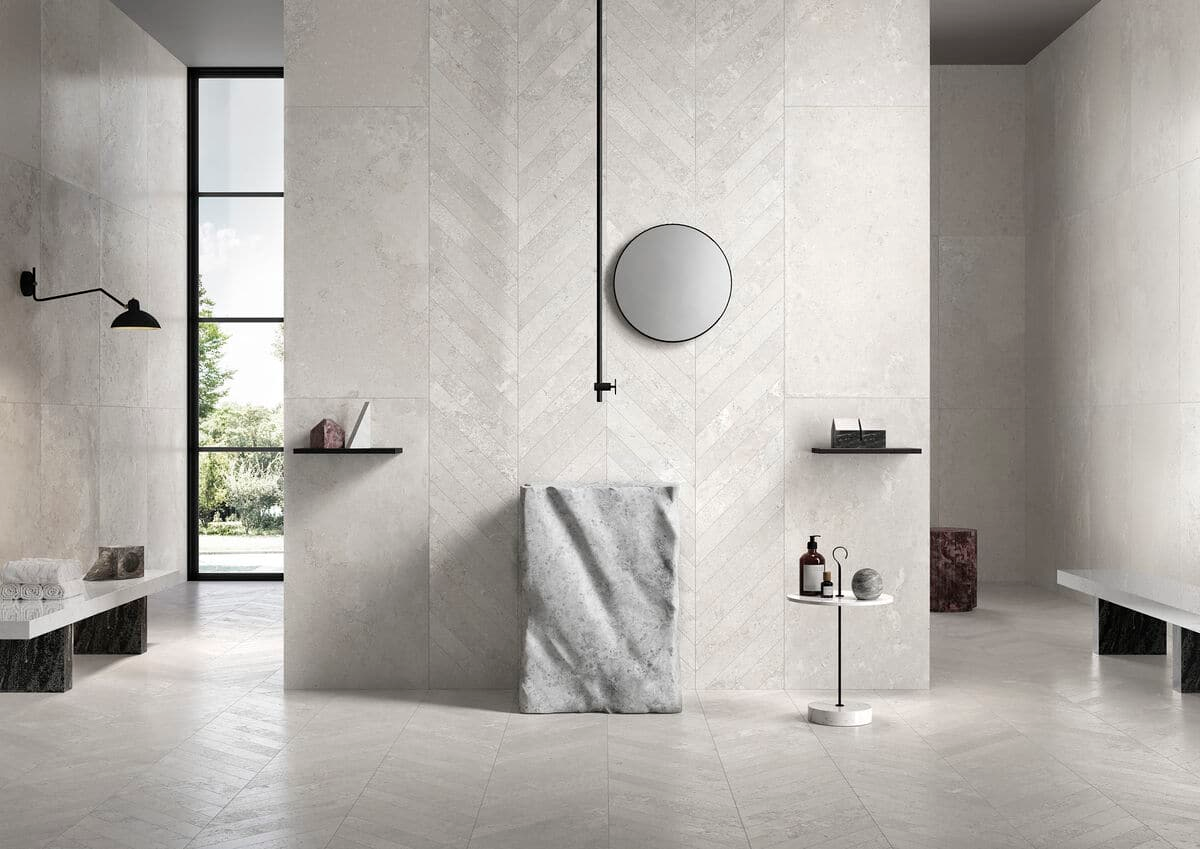 Minimalistische badkamer met lichte visgraat wandtegels, een ronde spiegel en moderne zwarte accenten voor een stijlvolle uitstraling.