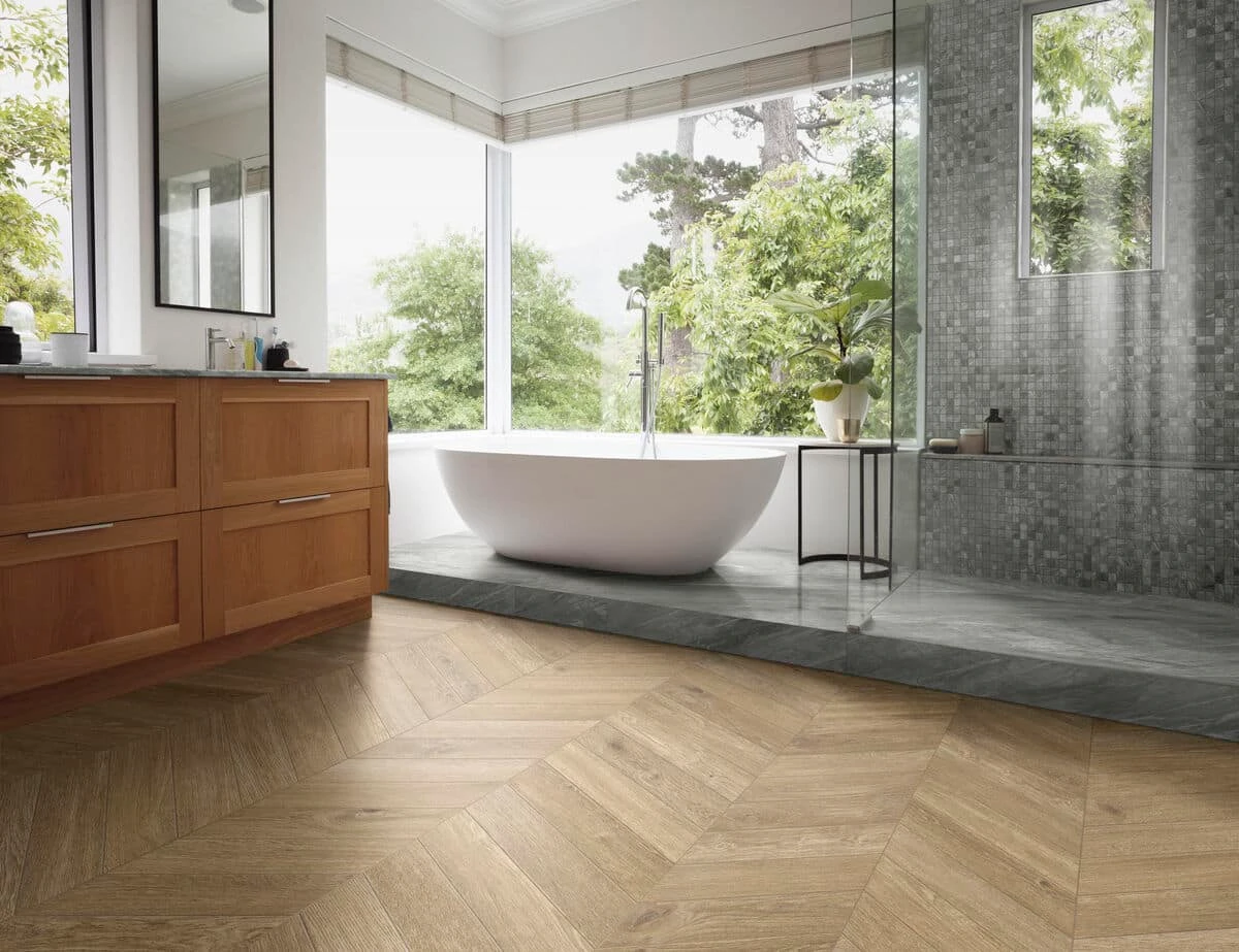 Luxe badkamer met grote ramen, houten wastafels, een vrijstaand bad en visgraat houtlook vloertegels voor een warme sfeer.