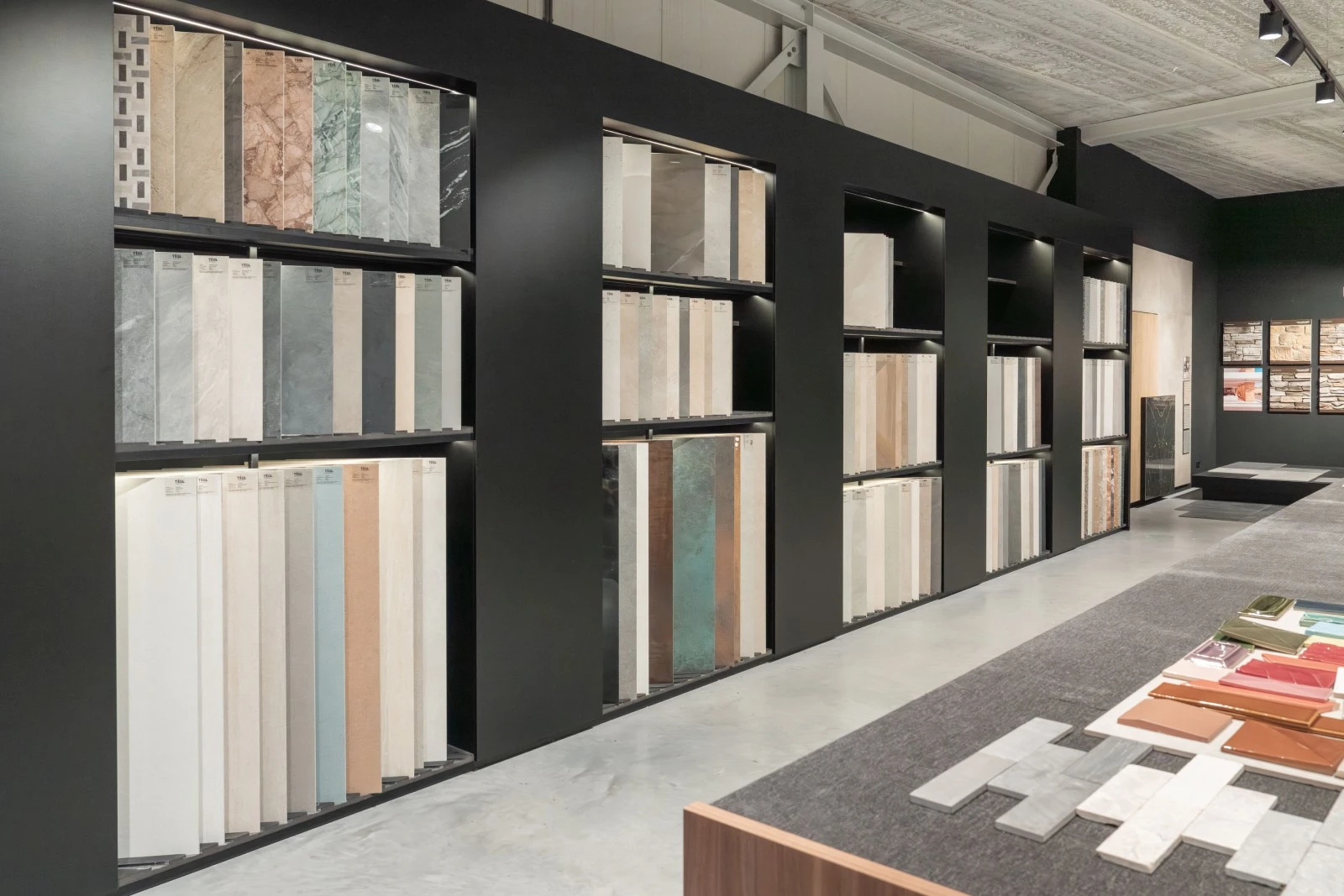 Groepjes van grootformaat tegels leunend tegen de muur in diverse soorten, maten en kleurtinten in de showroom van TÉGL