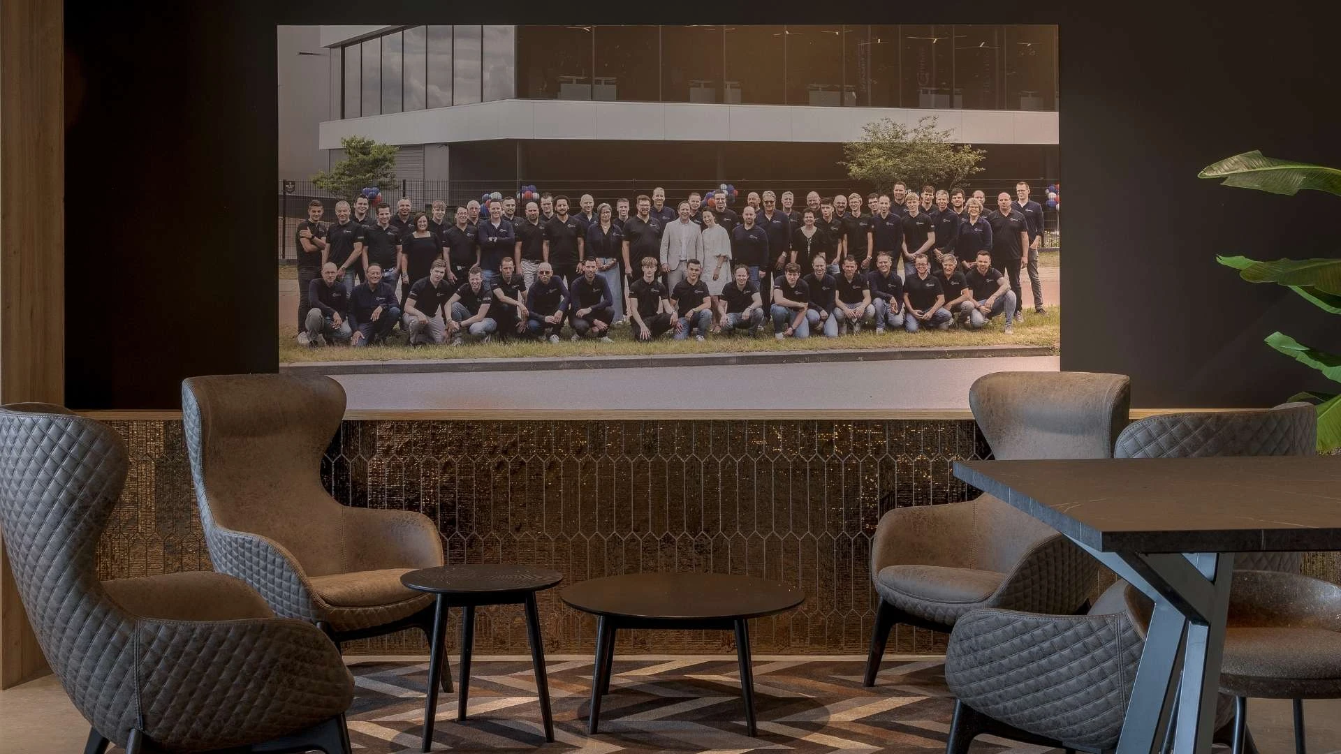 Impressie van een zithoek in een bedrijfspand. De wand heeft een lambrisering van patroon tegels.