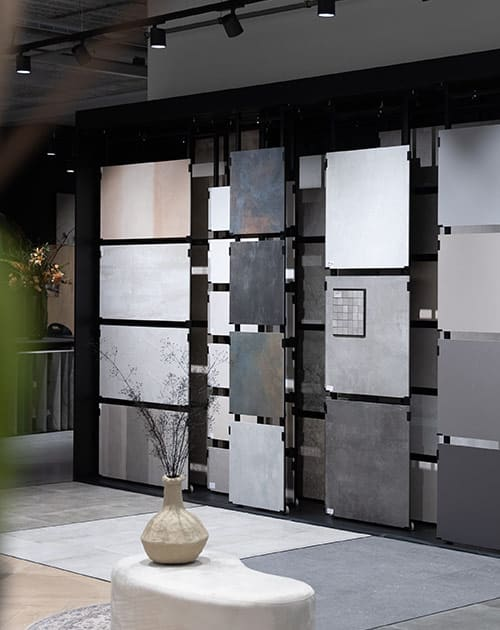 Verschuifbare rekken met grote natuursteenlook tegels in diverse aardse tinten in de showroom van TÉGL