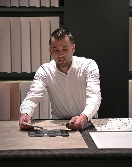 Mannelijke TÉGL specialist legt diverse tegel samples op de toonbank in de showroom