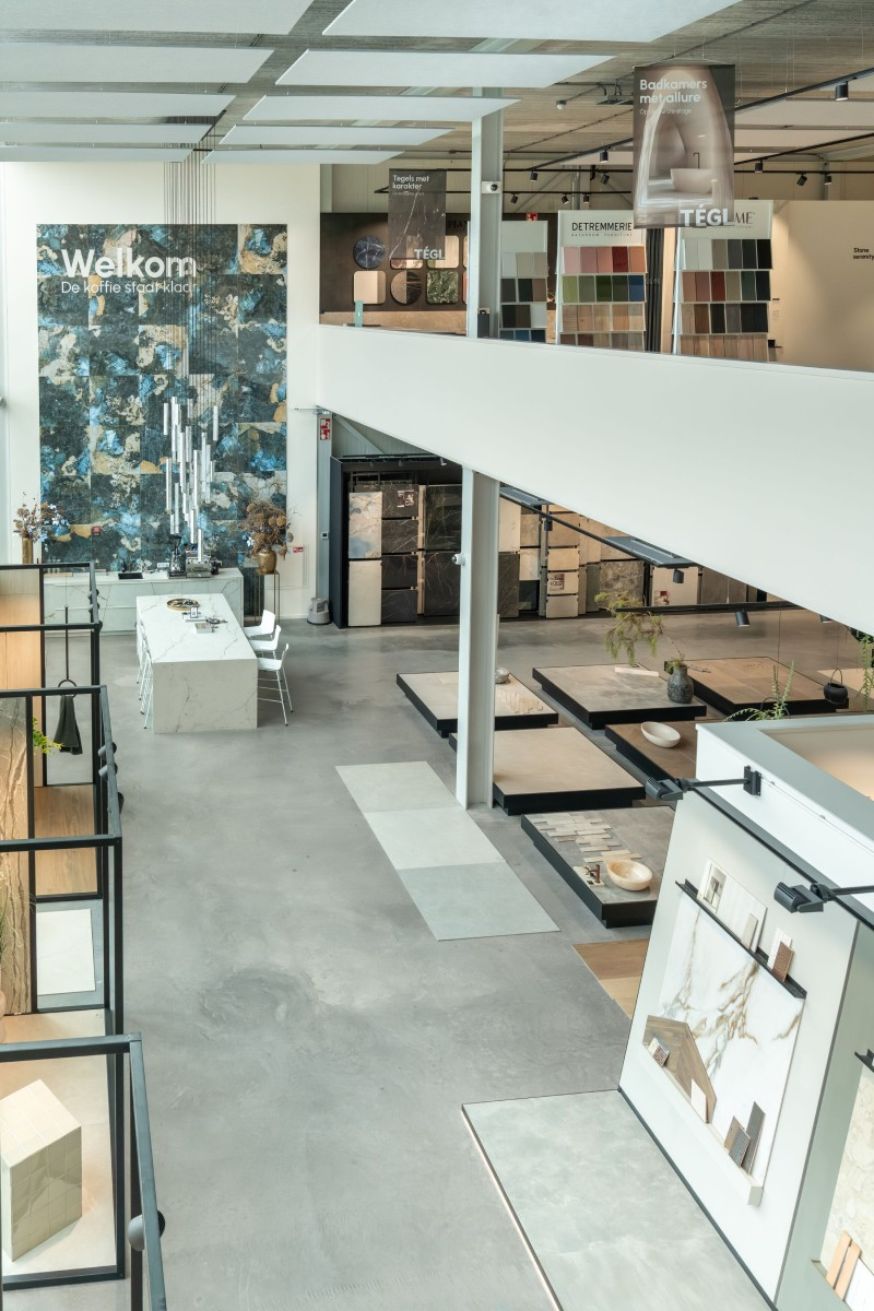 Verschuifbare rekken met grote natuursteenlook tegels in diverse aardse tinten in de showroom van TÉGL